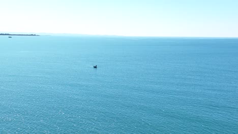 Aerial-orbit-around-lone-boat-in-massive-expanse-of-blue-open-ocean