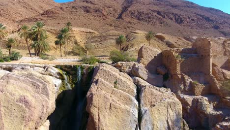 Drohnenaufnahme-Eines-Wasserfalls-Zwischen-Wüstenbergen-In-Bousaada,-Algerien