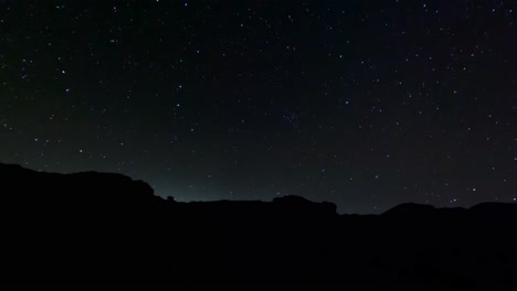 Sternenklarer-Nächtlicher-Zeitraffer-Mit-Zerklüfteter-Landschaft-Als-Silhouette-Im-Vordergrund