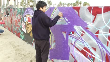 People-spray-painting-art-wall-at-beach