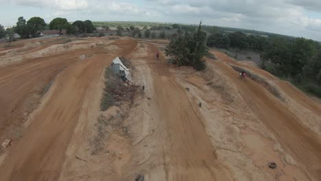 Wide-aerial-view-of-motocross-riders-practicing-on-dirt-track-jumps