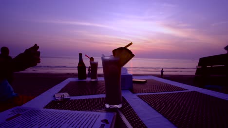 Cocktails-and-drinks-by-the-beach-during-sunset-with-unrecognizable-people-in-the-background