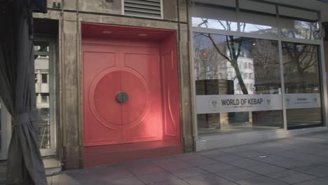 Bright-Red-Door-On-Urban-Street---Schlossplatz-In-Downtown-Stuttgart-in-4K,-Classic-Germany-Architecture,-Famous,-Red-Komodo-Cooke-Mini-S4i-Lens-Premium-Quality-|-News