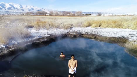 Zwei-Schwimmer,-Männlich-Und-Weiblich,-Stehen-Mittags-Im-Dampf-Der-Heißen-Quellen-Von-Saratoga-In-Provo,-Utah,-Mit-Schnee-überall-Auf-Dem-Boden
