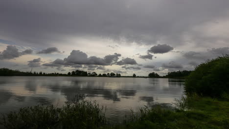 Serene-body-of-water-surrounded-by-trees-and-grass,-cloudy-day-timelapse