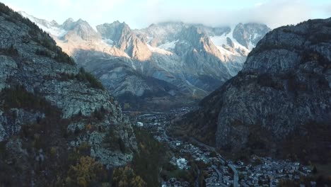 Calm-ascending-aerial-at-iconic-mont-blanc-from-Courmayeur,-Italy,-Aosta-Valley,-Italian-Alps-in-autumn-with-fall-colors-on-forest-and-trees