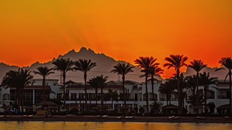 Time-lapse-De-La-Puesta-De-Sol-De-Hurghada:-Fascinante-Horizonte-Con-Palmeras,-Edificios-Y-Silueta-De-Montaña