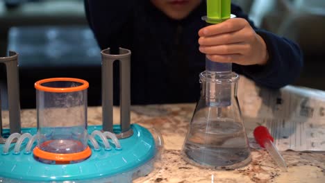 Kids-Science-Toys-For-STEM-Education:-Small-Hands-Using-A-Liquid-Plunger-To-Suck-Water-Out-Of-A-Beaker