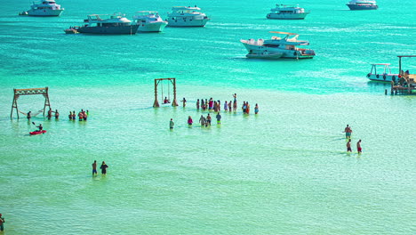 Turistas-Bañándose-En-Hurghada-Con-Yates-Anclados-En-Una-Playa-Cristalina-Del-Mar-Rojo