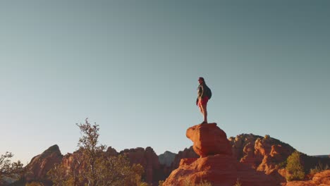 Young-30s-woman-stands-on-top-of-rock-on-mountain-in-Sedona