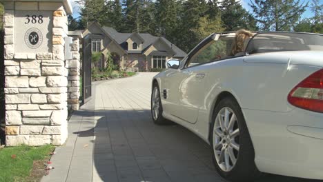 White-convertible-sports-car-enters-suburban-home-in-summer