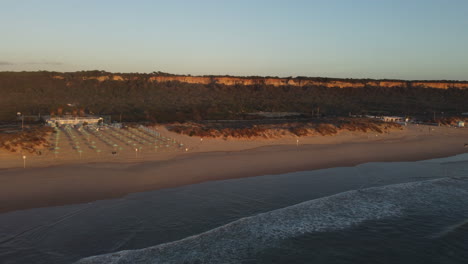 Drohnenaufnahme-Von-Costa-Da-Caparica-In-Der-Nähe-Von-Lissabon---Drohne-Fliegt-Bei-Sonnenuntergang-Am-Strand-Entlang