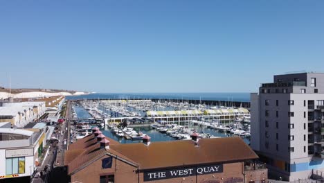 Aerial-reveal-of-Brighton-Marina,-West-Quay,-Boardwalk-and-White-Cliffs-on-a-sunny-day