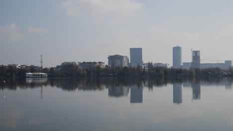 Establishing-Shot-Of-Office-Tower-Buildings,-Trees-And-Lake