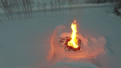 Drone-flight-over-big-bonfire-in-winter-landscape