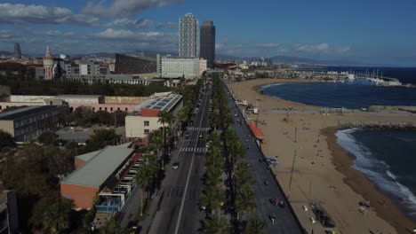 Toma-De-Drone-De-La-Playa-De-Barcelona---Drone-Está-Volando-A-Lo-Largo-Del-Paseo-Marítimo-Sobre-Una-Carretera-Con-Coches