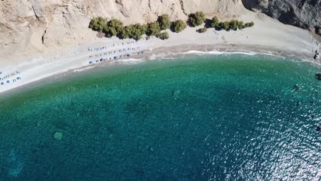 Tilt-Down-Drone-Aerial-Shot-Of-Glyka-Nera-Beach-under-Dramatic-Cliffs,-Area-of-Sfakia,-Greece