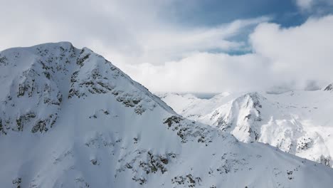 Schwenkende-Zeitlupen-Panorama-Drohnenaufnahme,-Die-Skifahrer-Und-Snowboarder-Zeigt,-Die-Den-Berg-Hinunterfahren
