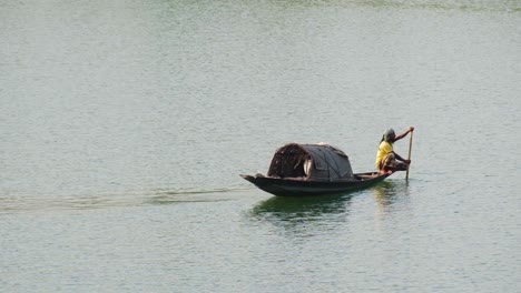 Asian-fisherman-paddles-while-he-sits-on-traditional-Asian-boat,-static