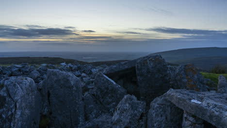 Timelapse-of-rural-nature-landscape-with-ruins-of-prehistoric-passage-tomb-in-the-foreground-during-dramatic-sunset-viewed-from-Carrowkeel-in-county-Sligo-in-Ireland