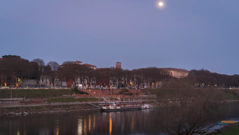River-Ticino-flows-near-the-center-of-the-city-of-Pavia,-background-city-traffic-and-movement-of-the-moon-in-the-sky,-Timelapse-30-fps