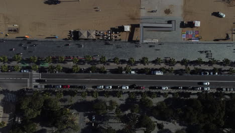 Drone-shot-of-Barcelona-beach---drone-is-ascending-in-birds-eye-view-over-a-street-next-to-promenade