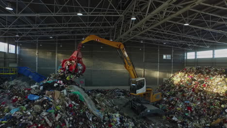 Aerial-view-showing-crane-transporting-and-sorting-trash-and-garbage-inside-hall