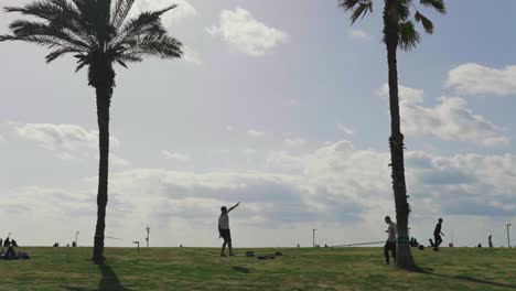 Young-man-slackline-tight-rope-walking-on-slack-over-grass-at-beach-in-Tel-Aviv-Israel