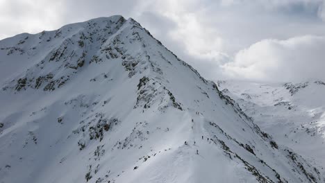 Schwenkende-Zeitlupen-Panorama-Drohnenaufnahme,-Die-Skifahrer-Und-Snowboarder-Zeigt,-Die-Den-Berghang-Hinunterfahren