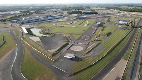 Aerial-view-flying-across-Silverstone-race-track-F1-motorsport-tarmac-circuit-corners-and-straights