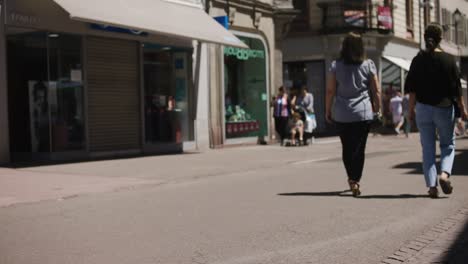 Two-women-walking-down-crowded-street-in-popular-tourist-shopping-area-in-Colmar,-France