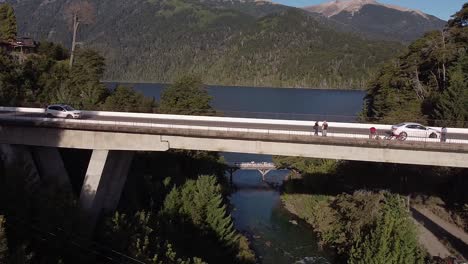 Brücke-über-Den-Fluss-Correntoso-Mit-Dem-See-Nahuel-Huapi-Und-Den-Bergen-Im-Hintergrund