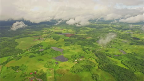 Green-and-vast-rural-landscape-and-clouds,-high-altitude-drone-view