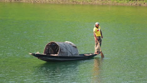 Pescador-Asiático-Se-Encuentra-En-Un-Barco-De-Pesca-Tradicional-De-Madera,-Río-Surma