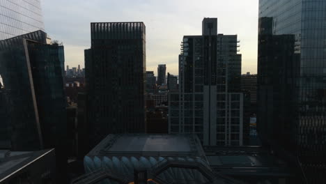 Ascending-aerial-view-in-front-of-the-Vessel-structure,-revealing-the-Lower-Manhattan-cityscape,-sunset-in-NY,-USA