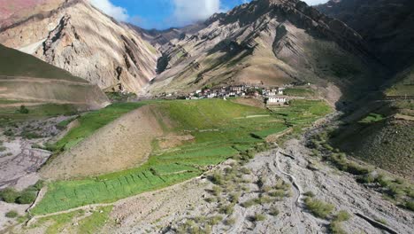 Impresionante-Paisaje-Montañoso-Con-Pueblo-En-Una-Colina-Llena-De-Exuberantes-Tierras-De-Cultivo-En-Pin-Valley-India,-Antena