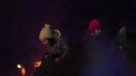 Two-little-girls-riding-together-on-a-dinosaur-in-amusement-park-at-night