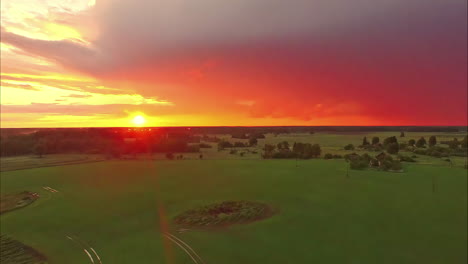 Red-vibrant-sunset-over-agriculture-fields,-aerial-drone-view