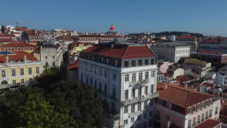 Drohnenaufnahme-Des-Bairro-Alto-In-Lissabon---Drohne-Steigt-Auf-Und-Blickt-Auf-Ein-Historisches-Gebäude-Mit-Der-Portugiesischen-Flagge-An-Der-Spitze