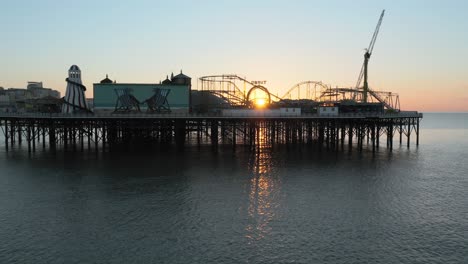 Brighton-pier-UK-and-at-sunrise,-with-sun-shinning-through-funfair