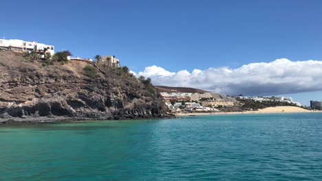 Vista-Panorámica-De-La-Costa-En-La-Isla-De-Fuerteventura-Barco-Canario-Navegando-Por-El-Océano-Atlántico-En-La-Playa-Del-Paraíso-Tropical