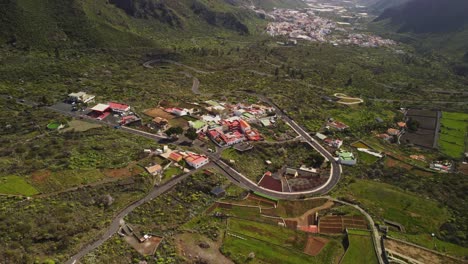 From-above-view-at-remote-spanish-village-and-winding-road-in-the-green-valley