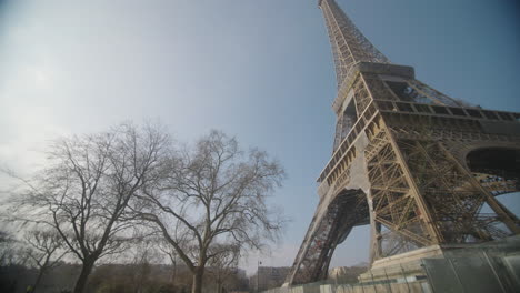 Mighty-Eiffel-tower-in-Paris,-France,-slow-pan-right-reveal,-blue-sky,-sunny-day