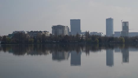 Cityscape-With-Office-Buildings,-Trees-And-A-Lake