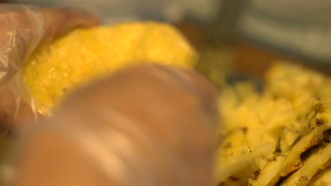 Kitchen-cleaver-used-to-remove-remaining-husk-parts-of-freshly-peeled-yellow-pineapple-fruit,-filmed-as-extreme-close-up