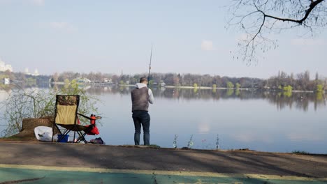 Fisherman-Cast-Fishing-Rod-In-Lake-Water-At-Morning