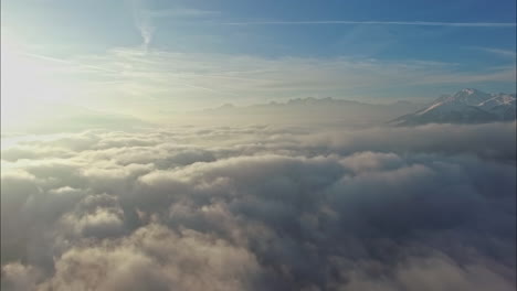 Sun-shinning-above-cloudscape-and-mountain-range,-aerial-drone-view