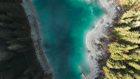 Drone-flying-through-clouds-showing-a-pristine-blue-water-lake-Caumasee-with-forests-around-in-Switzerland
