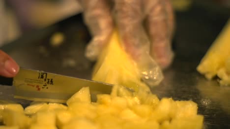 Slice-of-freshly-cut-yellow-pineapple-fruit-being-chopped-into-thin-pieces,-filmed-as-extreme-close-up-in-slow-motion