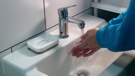 Seitenansicht-Einer-Frau,-Die-Sich-Unter-Dem-Wasserhahn-Im-Waschbecken-Im-Badezimmer-Die-Hände-Mit-Seife-Wäscht